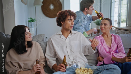 Curly guy talking friends sitting couch at living room. People watching sitcom