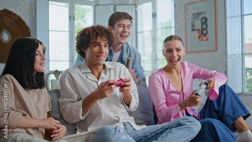 Obraz na płótnie Emotional buddies playing video game on home couch with happy friends closeup w salonie