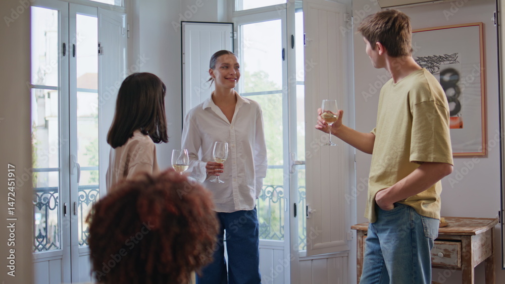 Talking friends gathering home holding drinks at living room home party together