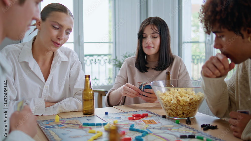 Diverse buddies playing board game together table closeup. Woman shuffling cards