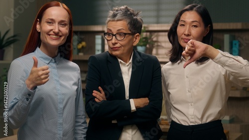 Three women showing thumbs up down gesture unsure unknown doubt choice employees office yes or no refusal approval question decision businesswomen business females girls positive negative boss choose