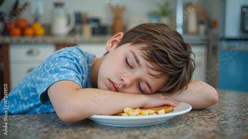 The kid fell asleep in a plate. Breakfast before school in the kitchen. The boy isn't enjoying his breakfast. Sleepy kid. Not ready for school.