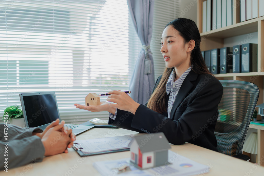Fototapeta premium Female real estate agent giving a key after signing a property contract, highlighting trust, homeownership, and the success of a real estate investment.