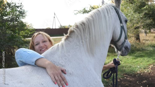 Happy woman pets her horse with love and care. Human and animal friendship concept. High quality 4k footage
