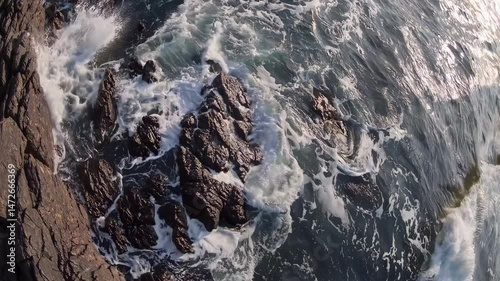 Powerful ocean waves surging, pounding rocky shoreline, generating dramatic white foam and spray