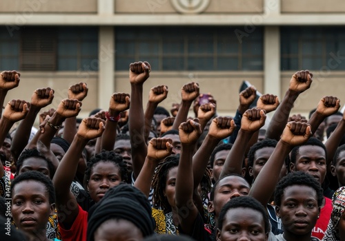A diverse group of people raises fists in the air during a protest, showing their unity.