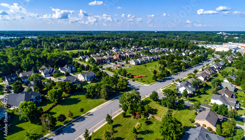 Aerial view of a suburban neighborhood showcasing homes, green lawns, and a clear blue sky (1)