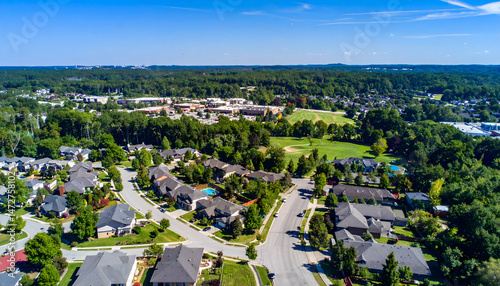 Aerial view of a suburban neighborhood with golf course, lush greenery, and clear blue skies