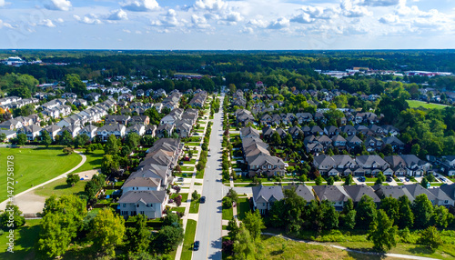 Aerial view of a suburban neighborhood with rows of houses lined along a quiet street, green parks
