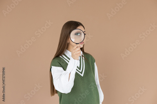 Happy young woman in uniform with magnifier on brown background