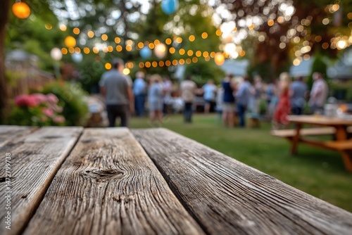 Wallpaper Mural Garden party, wooden table foreground, lights, people socializing in background Torontodigital.ca