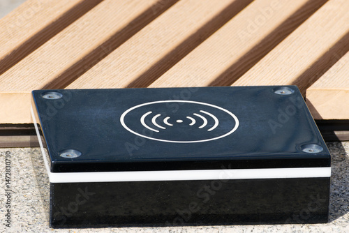 a device for wireless charging of electronic gadgets is installed near a bench in a city park