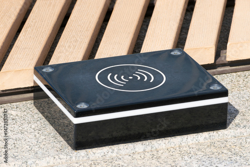 a device for wireless charging of electronic gadgets is installed near a bench in a city park