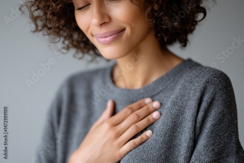 A close-up of a woman with a gentle smile, placing her hand over her heart, conveying feelings of gratitude, warmth, and connection, embodying the power of human emotion.