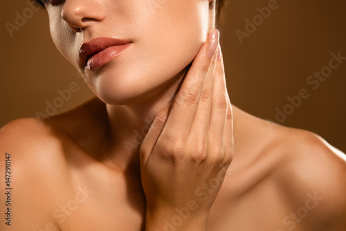 Close-Up Portrait of a Young Woman Touching Her Jawline Against a Neutral Backdrop
