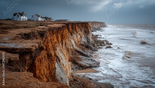 Dramatic coastal scene with houses perched atop eroding cliffs, showcasing the raw power of nature.