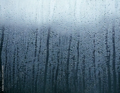 Condensation, fog, moisture, droplets, and water are beautifully captured in a closeup view, revealing intricate, natural patterns formed on a smooth window glass surface, emphasizing delicate texture