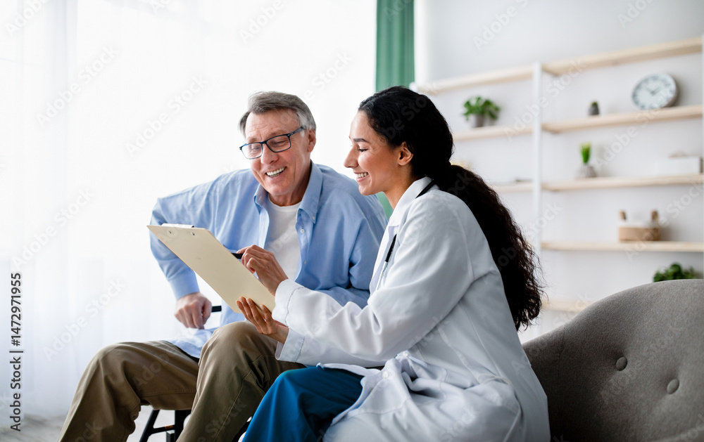 Obraz premium Young doctor asking senior impaired male patient in wheelchair to sign insurance policy at home. Handicapped elderly man putting his signature under surgery consent form, reading medical document