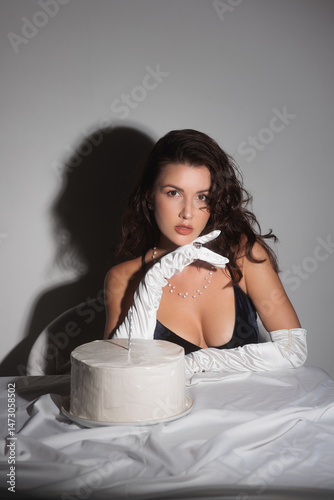Schilderij op canvas Elegant Woman in Black Dress Posing with White Cake for Glamorous Shoot