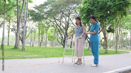 Elderly woman holding a cane being cared for by a female nurse in the park, natural therapy concept, employee or caregiver for the elderly