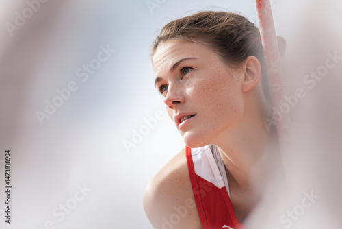 female athlete captured in midair during pole vault jump positioned on left side of frame