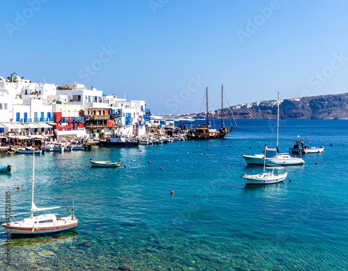 Greek harbor view with docked sailboats and clear turquoise water