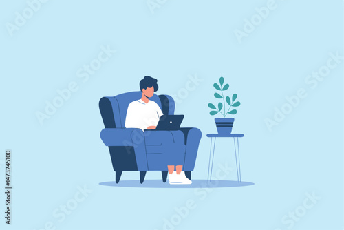 Man sitting in blue armchair working on laptop with houseplant beside him