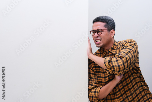 A man pushing a blank white wall with full of effort photo