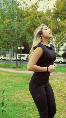 Latina woman jogging in green urban park and pausing to rest