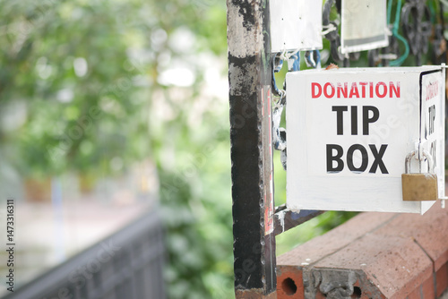 Donation tip box located in a community area with greenery photo