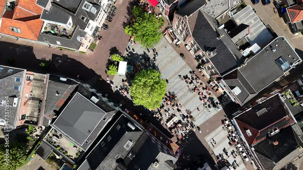 Relaxing people and pedestrian in dutch city during Kings Day. Aerial top down landing. Sunny day in dutch market center square. Green tree in spring. Celebration King Willem Alexander at Koningsdag