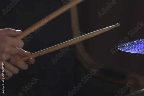 Hands hold the drumsticks while playing