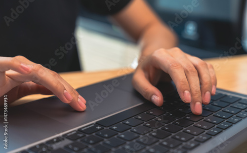 Businessman hand typing on laptop and working on computer on wooden table.