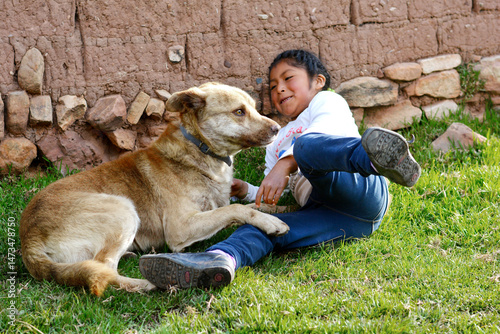Little aymara girl playing with a dog.