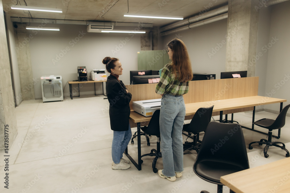 Obraz premium Two Businesswomen Engaged in Discussion in a Modern Open Workspace