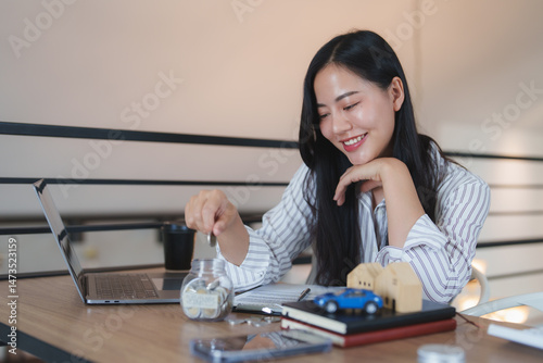 Happy asian businesswoman saving money for car and house using laptop