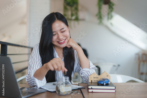 Happy asian businesswoman saving money for house and car purchase