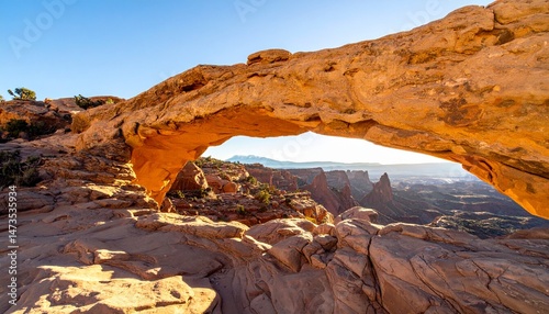 Stone arch overlooks a scenic canyon landscape, bathed in warm sunlight