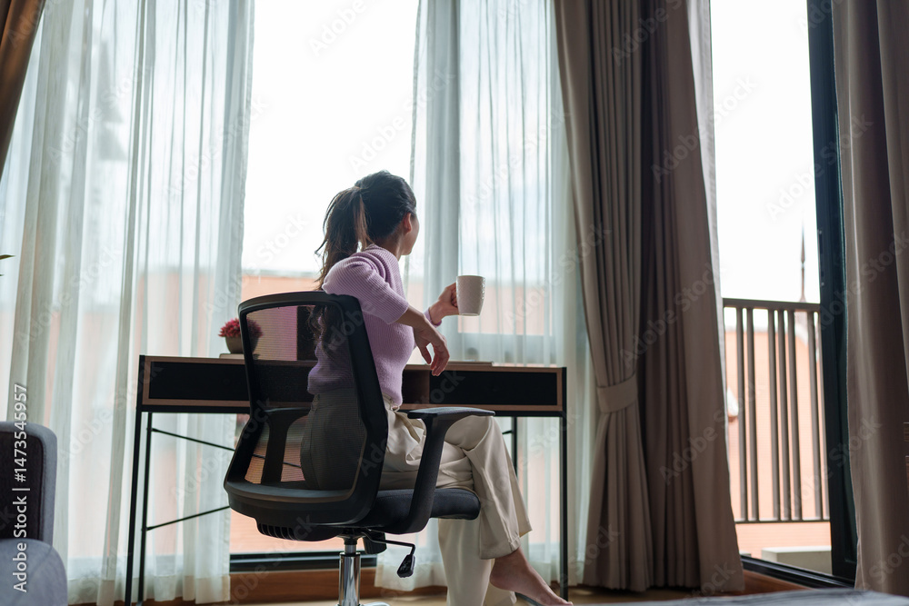 Fototapeta premium Businesswoman relaxing with coffee, enjoying view from office window