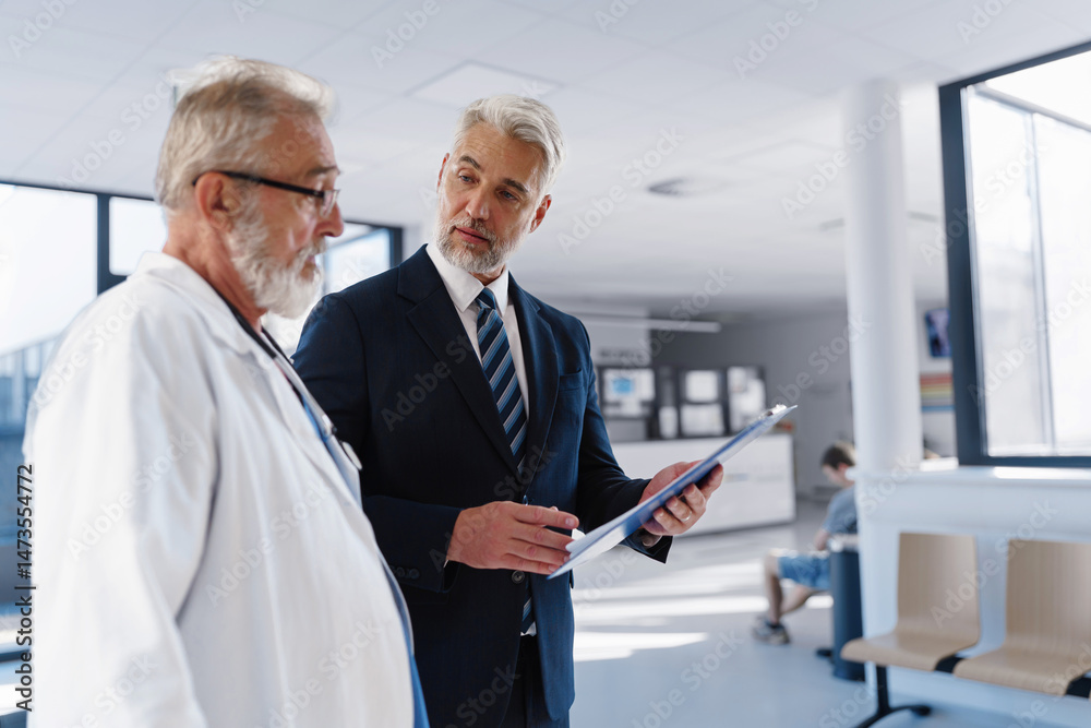 Fototapeta premium Doctor talking with hospital manager, walking down hospital hallway.