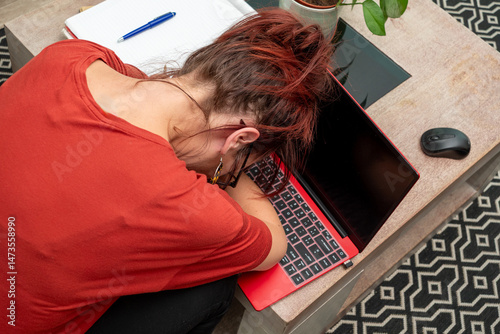 Woman is sleeping on a table with a laptop on her lap