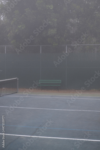 single green bench at tennis court with grey fog