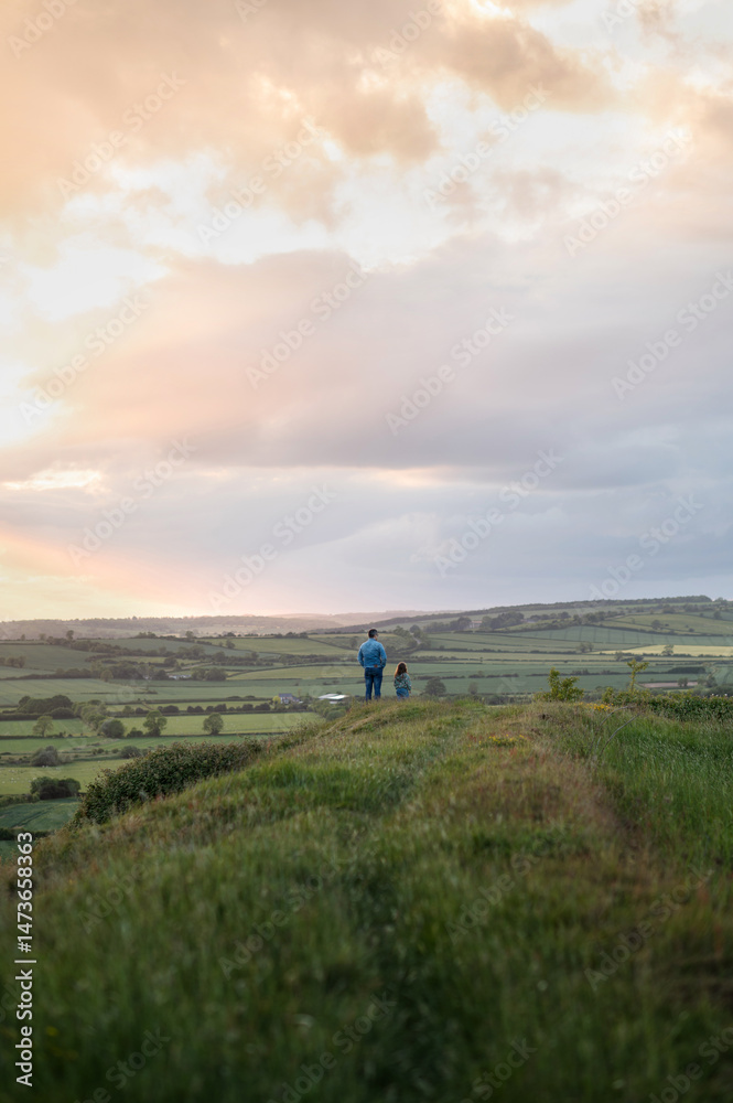 Father and daughter staying on the hill and looking at the valley. Father and daughter staying on the hill and looking at the valley.