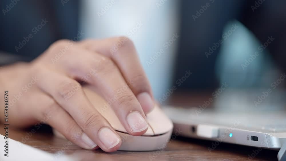 A person is using a computer mouse. The mouse is on a table. The person is wearing a suit
