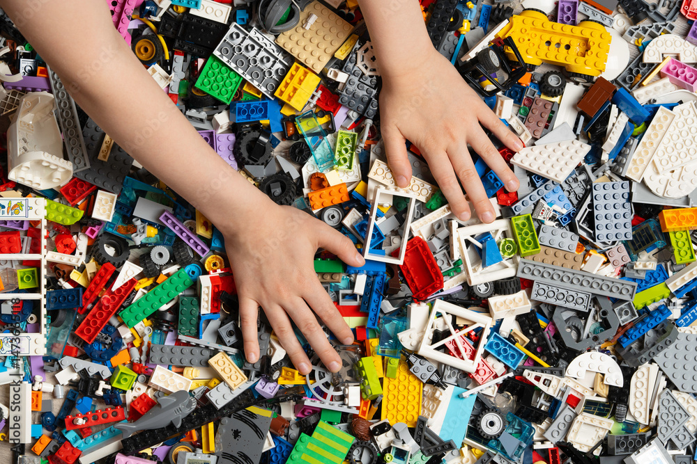 Fototapeta premium Illustrative editorial of Lego colorful assortment of plastic building blocks constructor in kid hands. Lego is a world famous company based in Billund, Denmark. KHARKIV, UKRAINE - 11 May 2025..