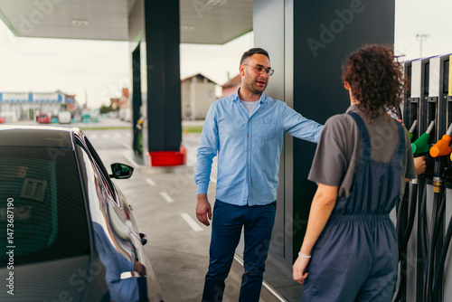 Friendly gas station attendant assists a customer in selecting the appropriate fuel type for their vehicle, ensuring a smooth and efficient refueling experience