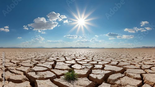 a cracked earth scene under a bright sun with a few clouds in the sky. It evokes the emotion of drought and climate change