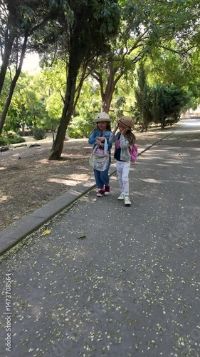 Happy children. Two girls walking in the park. Two little sisters walking together, talking. Best friends