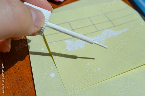 Fotografija Hand applying correction fluid to paper table on sticky note