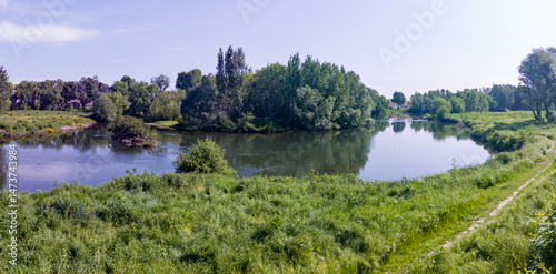 Obraz na płótnie Landscape with grass field, river and blue sky w salonie